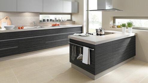 Impression einer Küchengestaltung mit Kochinsel mit Edelstahlabzug und dunklen Fronten